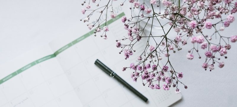 日历2025打印模板示例，A4横版全年日历表铺开在桌面上，红色标注节假日，灰色标注调休补班日